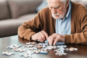 Starszy mężczyzna układa puzzle, co jest skutecznym sposobem na zapobieganie demencji.