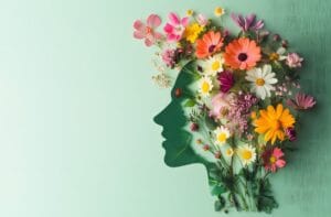 Zielony profil twarzy otoczony kolorowymi kwiatami symbolizuje naturalne wsparcie dla pamięci i koncentracji.