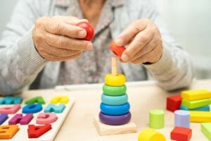 Starsza osoba układa klocki, co jest ważne dla zapobiegania demencji.