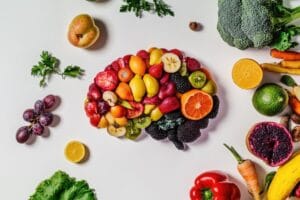 Różnorodne owoce i warzywa ułożone w kształt mózgu symbolizują dietę wspierającą zdrowie psychiczne.