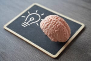 Model mózgu na tabliczce z rysunkiem żarówki jako symbol profilaktyki zdrowia mózgu.