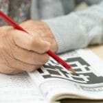 Senior rozwiązuje krzyżówkę, co pomaga w zapobieganiu demencji.