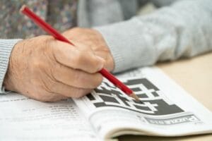 Senior rozwiązuje krzyżówkę, co pomaga w zapobieganiu demencji.