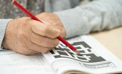 Senior rozwiązuje krzyżówkę, co pomaga w zapobieganiu demencji.
