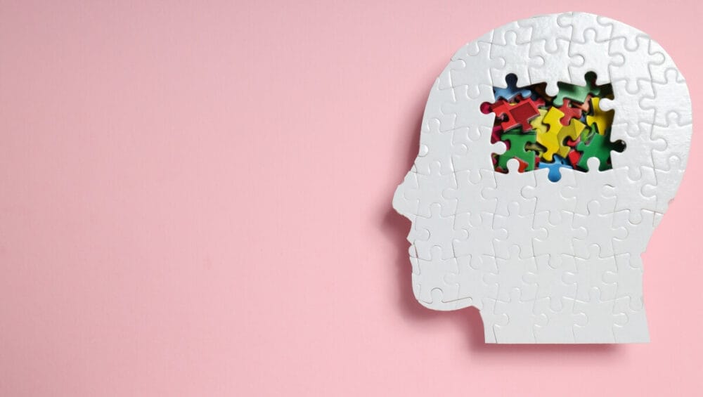 Profilaktyka zdrowia mózgu jest kluczowa, co symbolizuje puzzle w kształcie głowy na różowym tle.