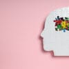 Profilaktyka zdrowia mózgu jest kluczowa, co symbolizuje puzzle w kształcie głowy na różowym tle.