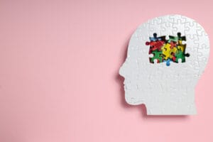 Profilaktyka zdrowia mózgu jest kluczowa, co symbolizuje puzzle w kształcie głowy na różowym tle.