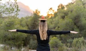 Osoba stojąca na świeżym powietrzu z książką i jabłkiem na głowie, co ilustruje naturalne sposoby na stres.
